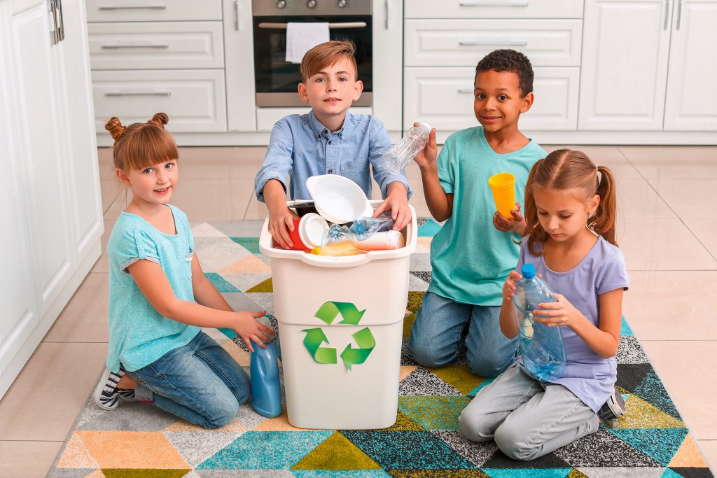 Little children and container with trash in kitchen. Concept of recycling; Shutterstock ID 1569956746; Kostenstelle: -; Lieferdatum: -