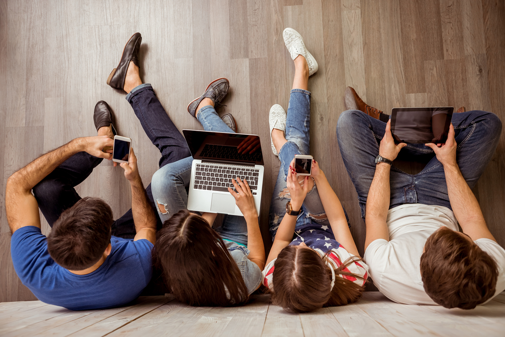 Group,Of,Attractive,Young,People,Sitting,On,The,Floor,Using