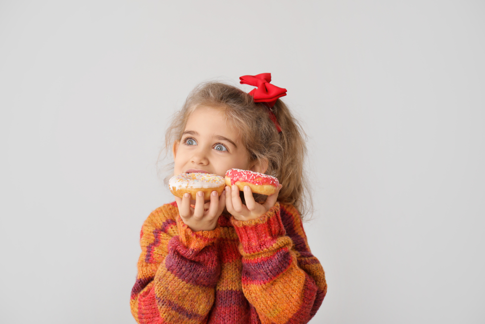 Cute,Little,Girl,With,Tasty,Donuts,On,Grey,Background