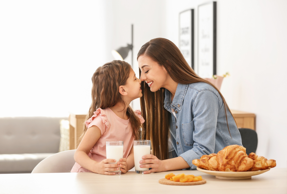 Mother,And,Daughter,Having,Breakfast,With,Milk,At,Table