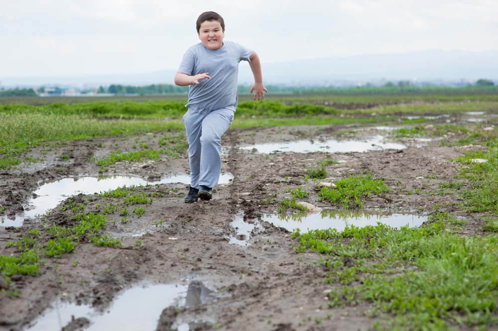 Fat,Boy,Running,In,The,Field,Among,The,Mud,And