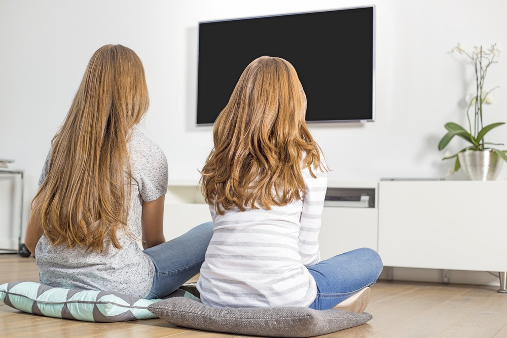 Rear,View,Of,Siblings,Watching,Tv,At,Home