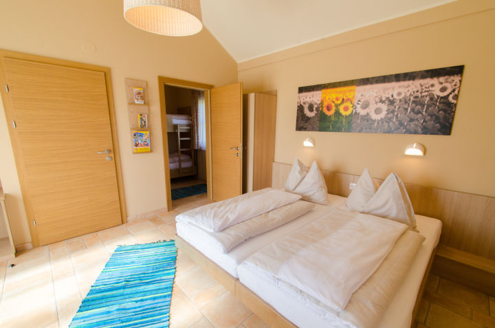 Doppelbett im Sommerhaus im JUFA Hotel Neutal Landerlebnis mit Wandbild. Der Ort für erlebnisreichen Natururlaub für die ganze Familie.