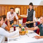 Sie sehen eine Familie beim Abendessen im JUFA Alpenhotel Saalbach****. Der Ort für erholsamen Familienurlaub und einen unvergesslichen Winter- und Wanderurlaub.