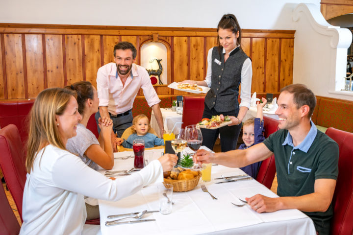 Sie sehen eine Familie beim Abendessen im JUFA Alpenhotel Saalbach****. Der Ort für erholsamen Familienurlaub und einen unvergesslichen Winter- und Wanderurlaub.