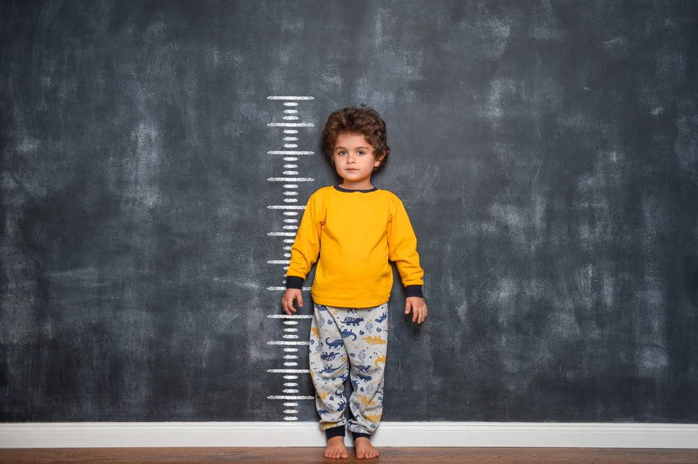 Funny,Smiling,Little,Child,With,Measures,Of,Growth,On,Blackboard