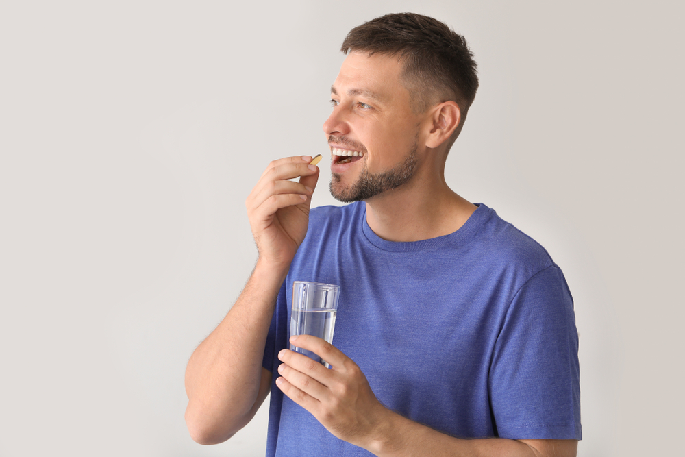 Man,Taking,Pill,On,Light,Background