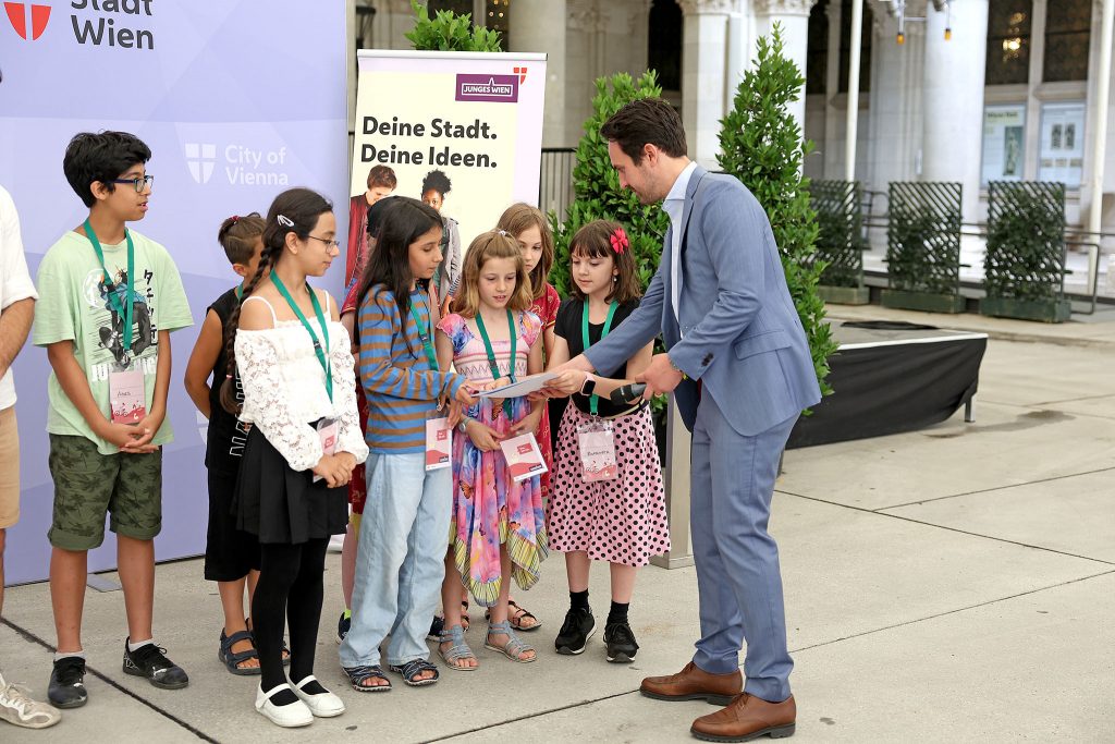 Vizebürgermeister Christoph Wiederkehr gratuliert den Sieger*innen der Kinder und Jugendmillion: Ideengeber*innen für „Wir retten die Bienen“.