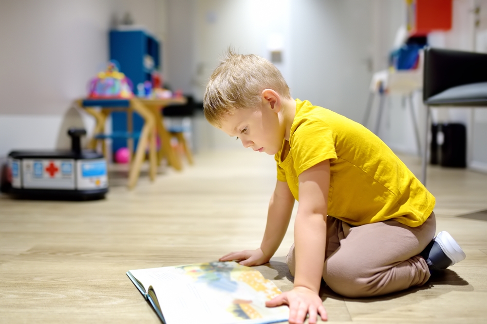 Cute,Little,Boy,Reading,A,Book,On,The,Floor,In