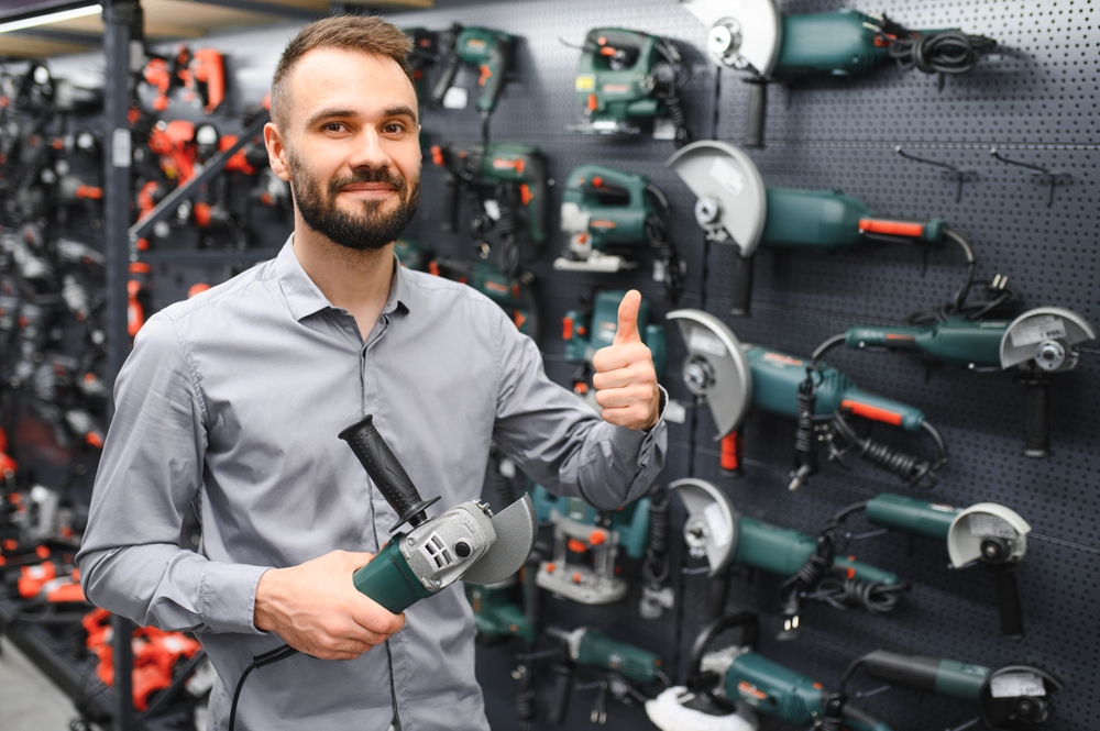 Confident,Smiling,Salesman,On,Foreground,In,Power,Tools,Store.