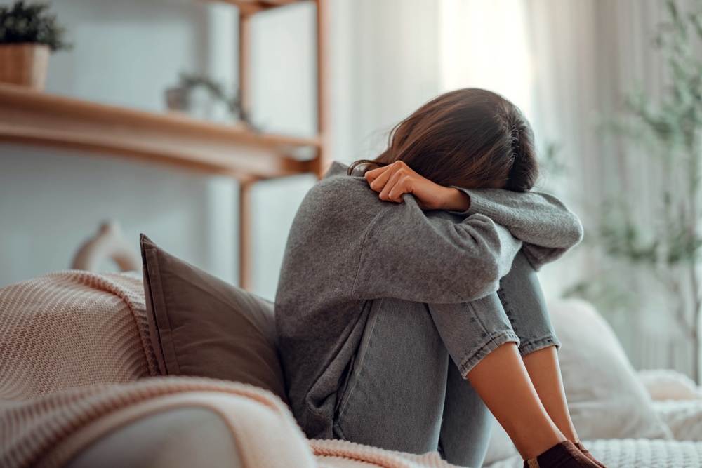 Depressed,Young,Woman,Sitting,On,Couch,In,The,Living,Room