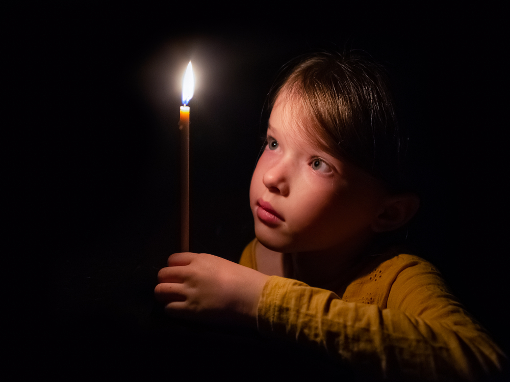 Little,Girl,Prays,And,Looks,At,A,Burning,Candle,In